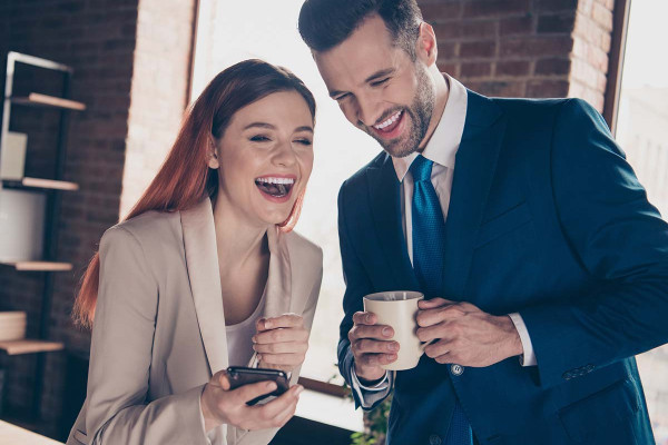Lustige Bürosprüche: Kollegen lachen miteinander über lustige Sprüche für die Arbeit