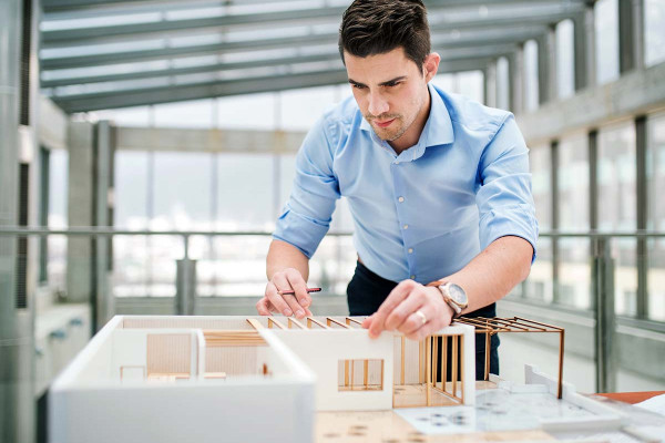 Architekt während der Arbeit mit einem Model (Gebäudeentwurf und Planung)